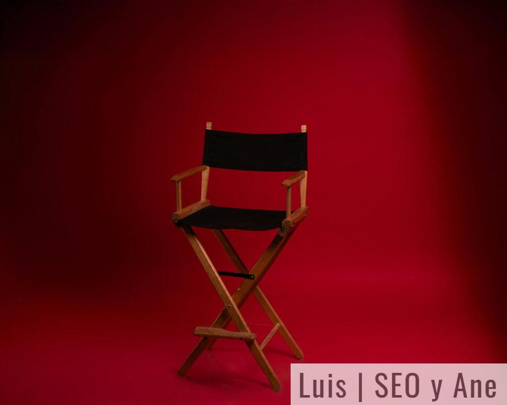 A wooden director's chair against a vibrant red backdrop, symbolizing film industry authority.